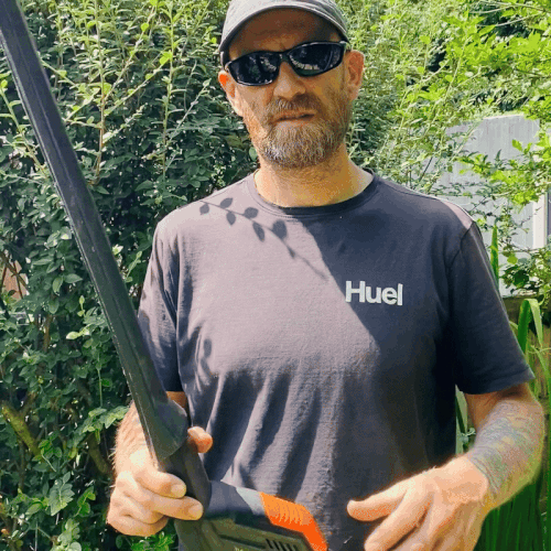 Close-up of Worx WG252E cordless pole trimmer laid across gardener’s chest while adjusting cutting head