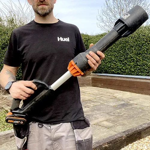 A gardener holding the Worx WG543E cordless leaf blower outdoors, demonstrating its lightweight design and comfortable one-handed use.